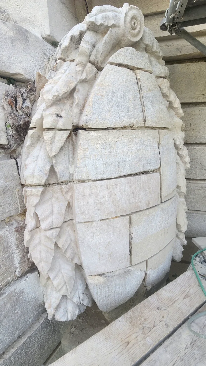 Grand médaillon sculpté en pierre en cours de restauration, vue latérale